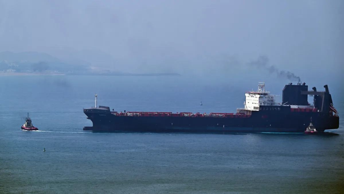 A tugboat guides a ship at the Khor Fakkan Container Terminal on the Gulf of Oman
