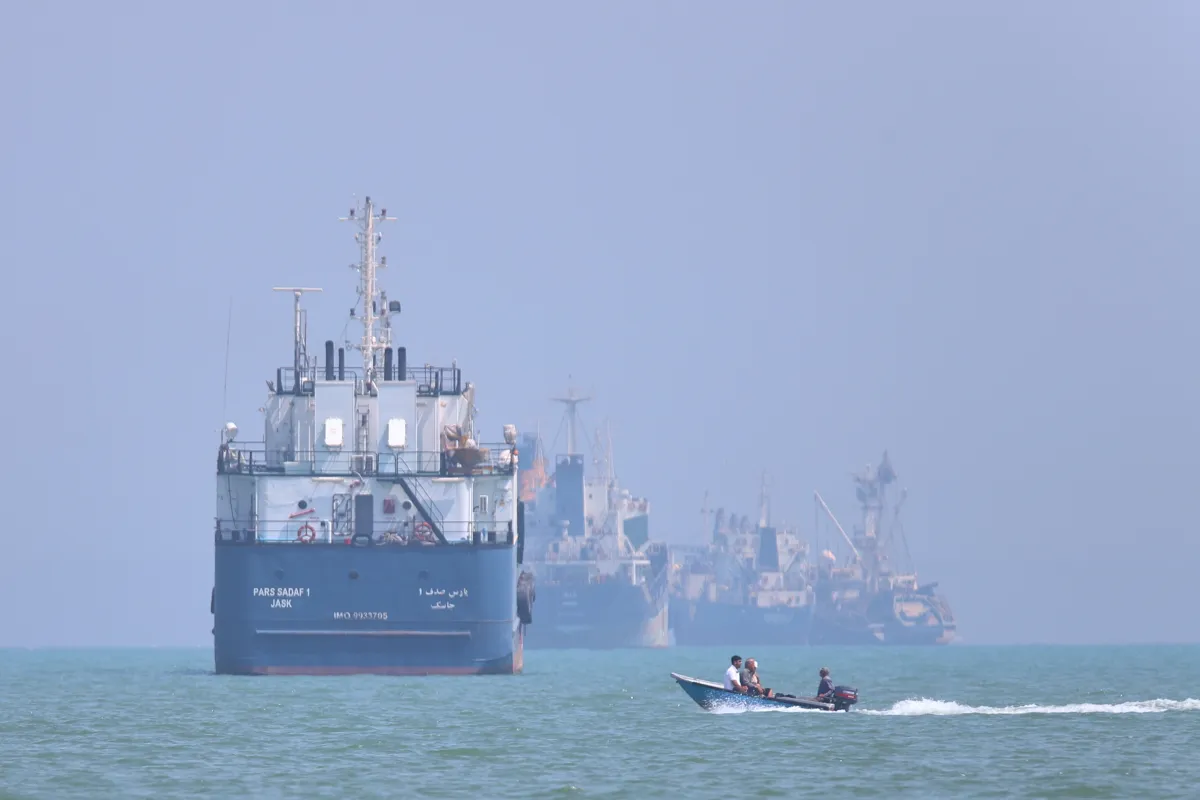 A small motorboat passes anchored vessels in the Strait of Hormuz off Bandar Abbas, Iran