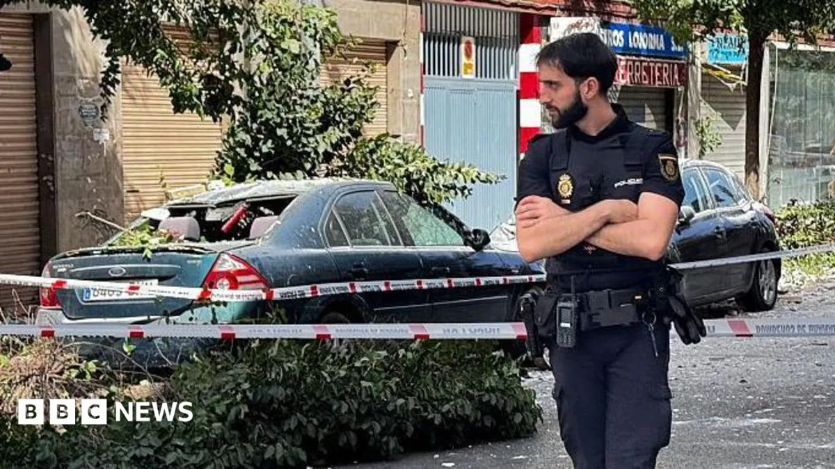 A policeman stands on a street next to a damaged car after the Granada earthquake